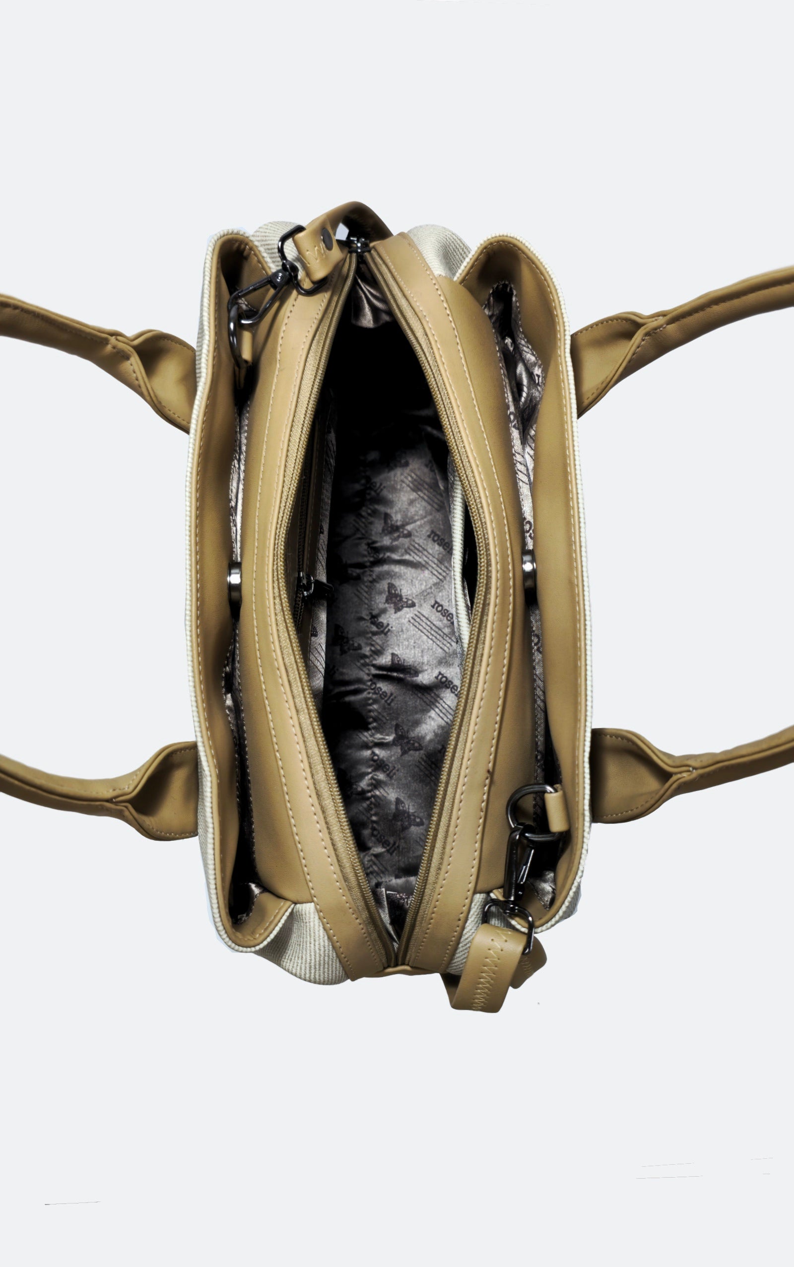 An overhead view of a beige leather handbag with its main compartment open, showing a black and white patterned lining, on a light gray background.