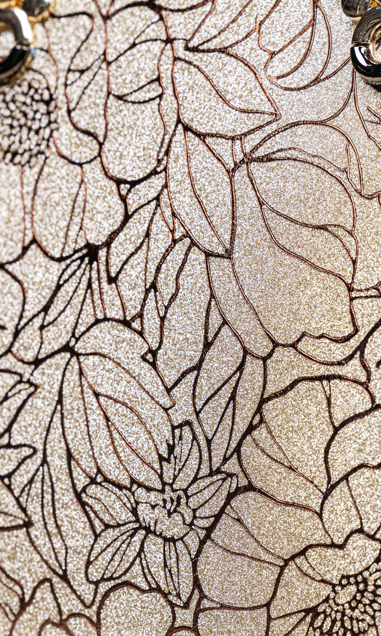 Close-up of a glittery champagne beige surface with an allover black floral line-art pattern.