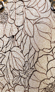 Close-up of a glittery champagne beige surface with an allover black floral line-art pattern.