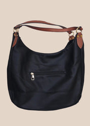 Black leather handbag with brown accents on a beige background back