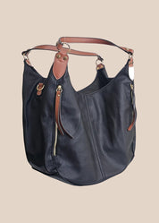 Black leather handbag with brown accents on a beige background side view