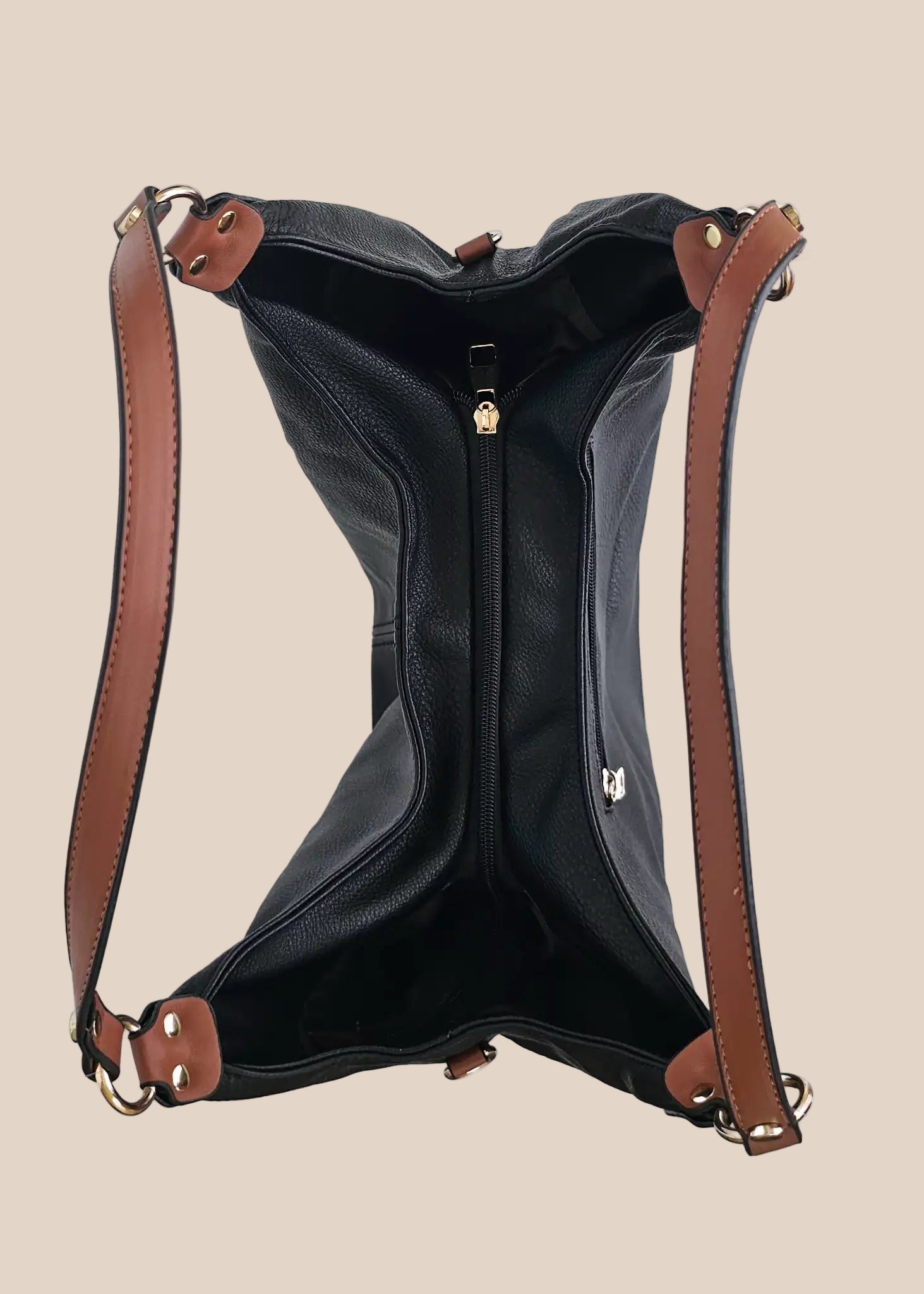 Black leather handbag with brown accents on a beige background top view