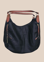Black leather handbag with brown accents on a beige background front