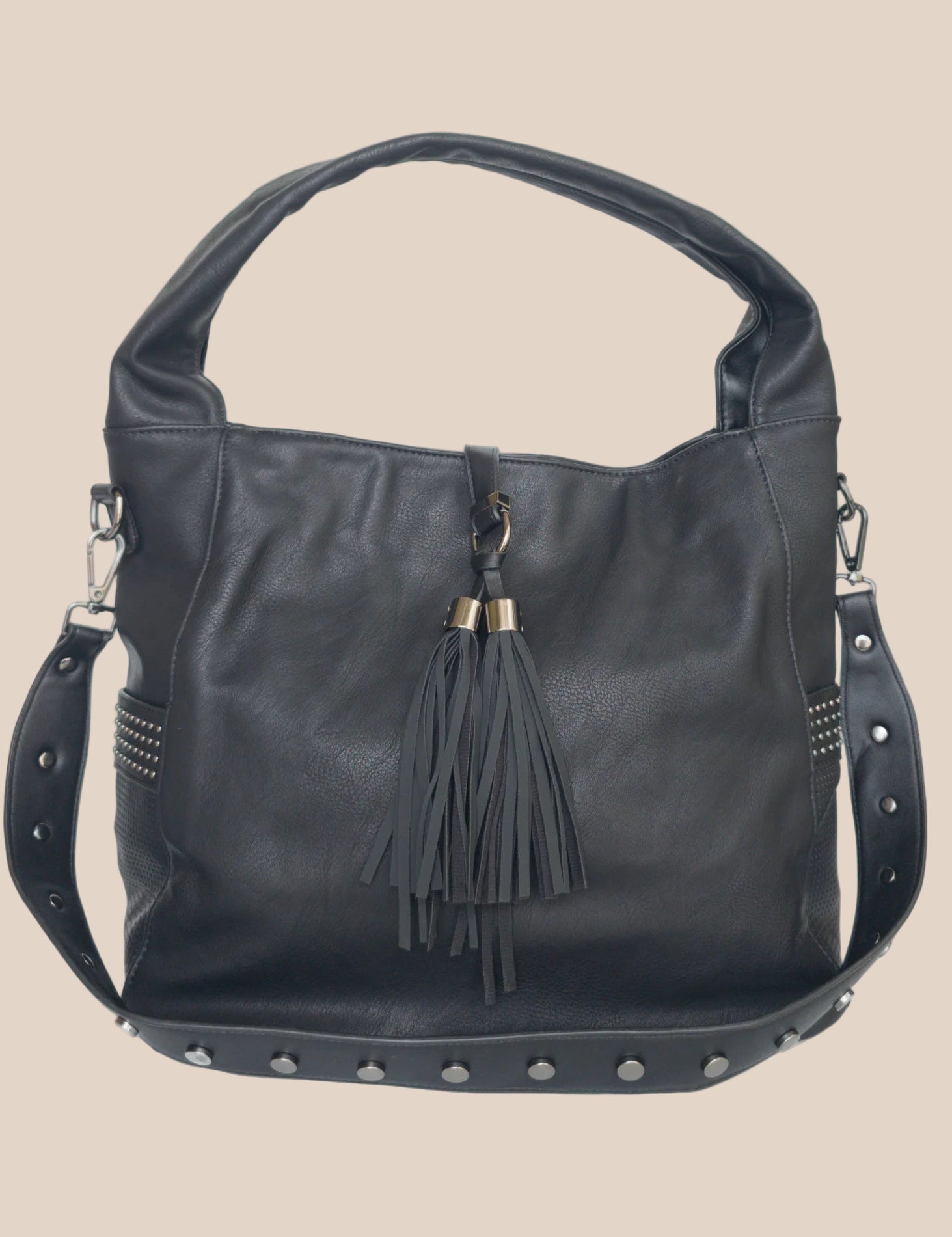 Black handbag with tassel and studs on a beige background back view