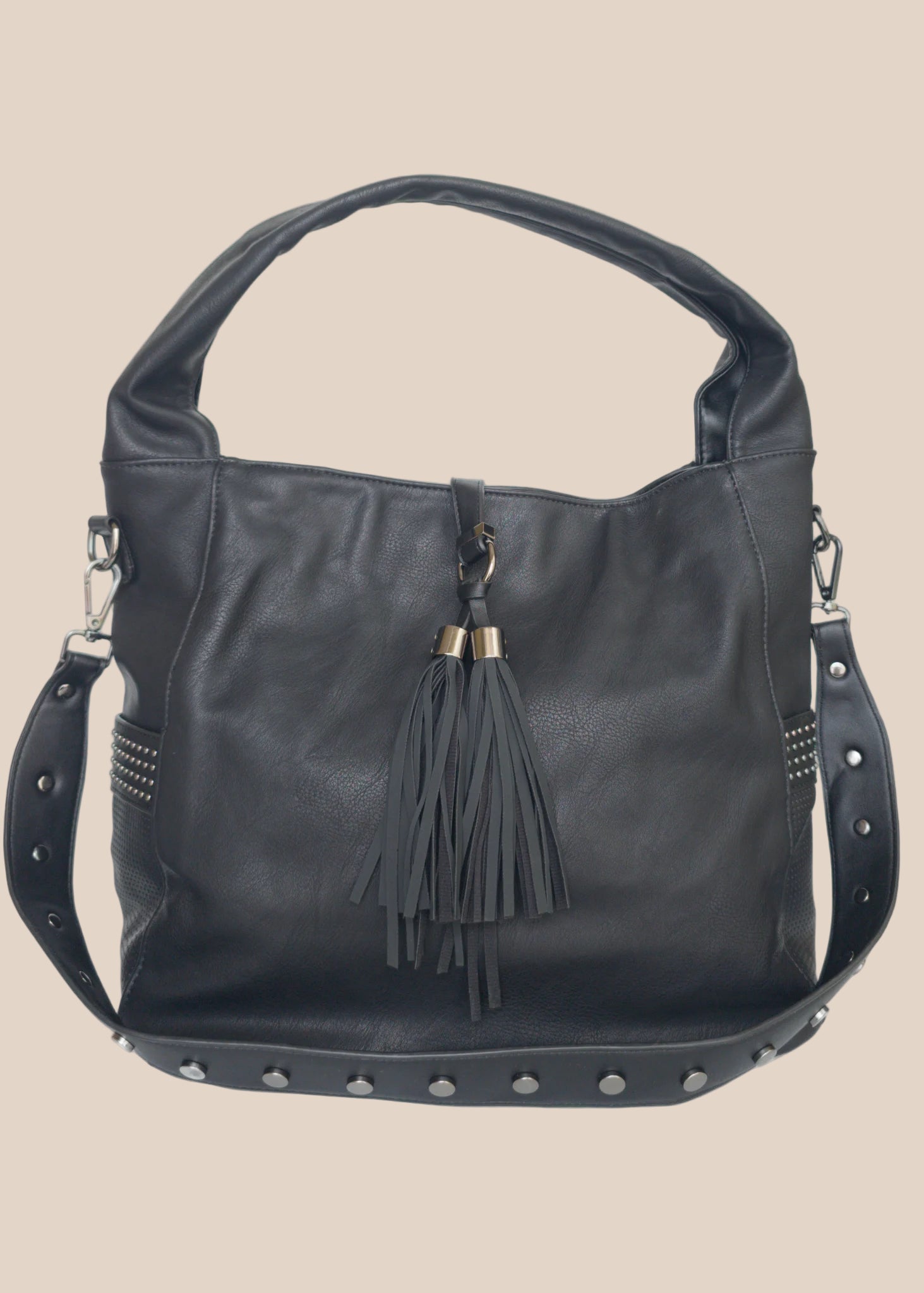 Black handbag with tassel and studs on a beige background back view