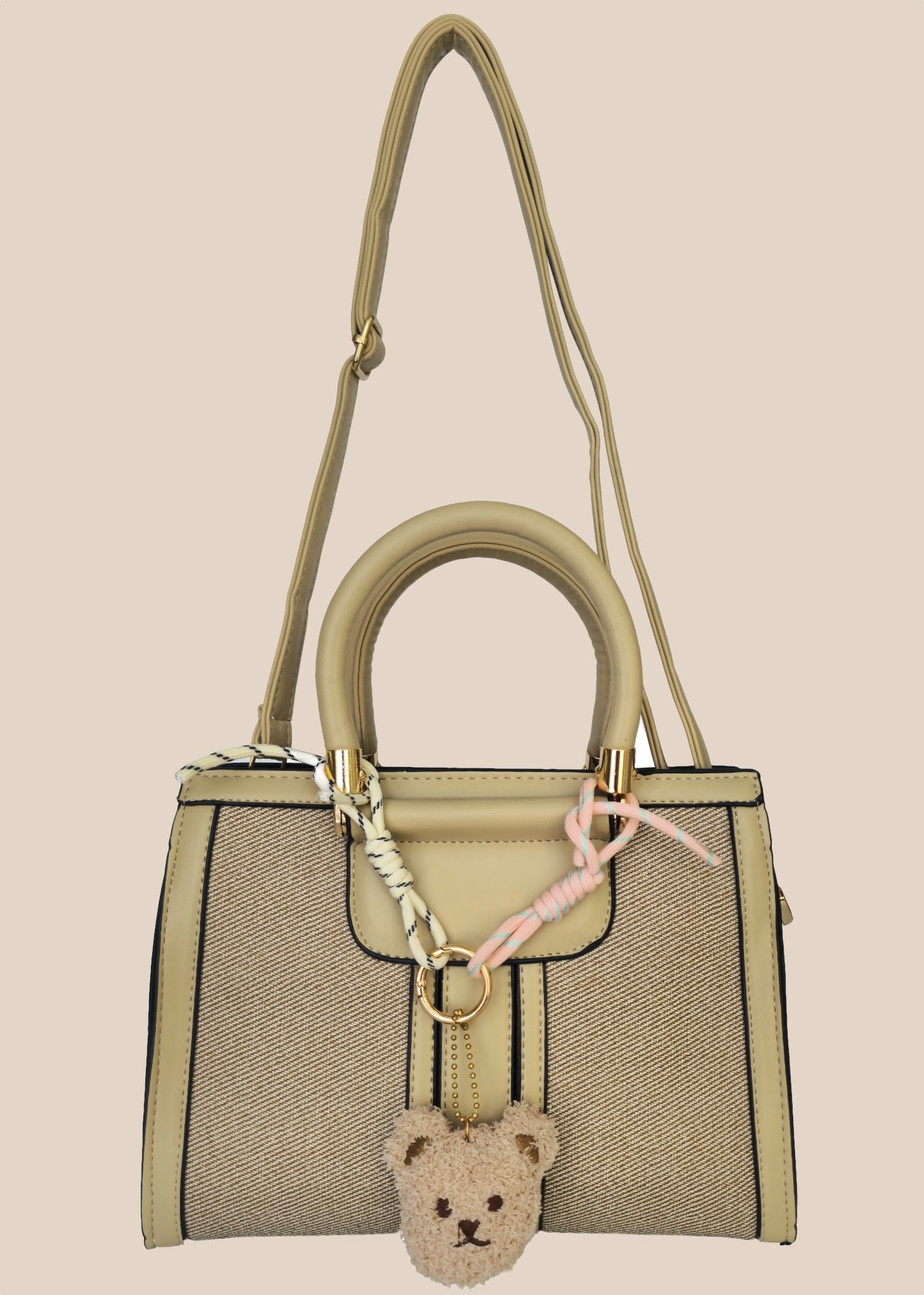 Handbag with a teddy bear charm on a beige background