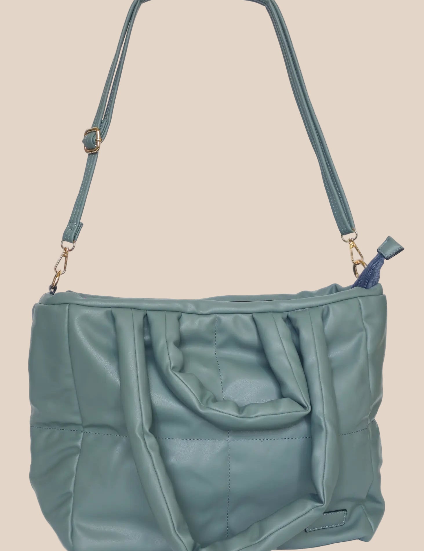 Teal quilted form handbag with a strap and handles