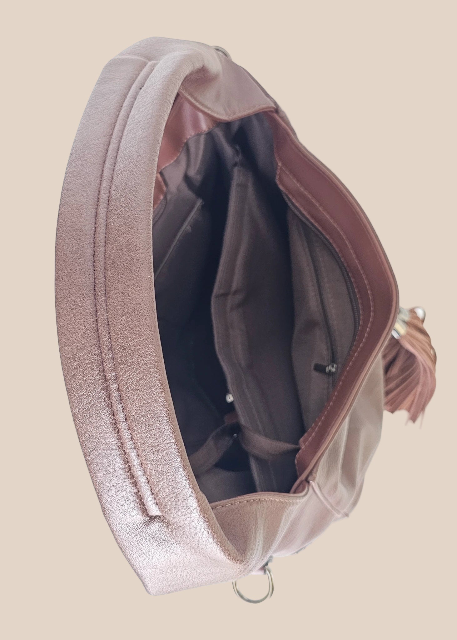 Brown leather handbag with a tassel on a beige background inside view