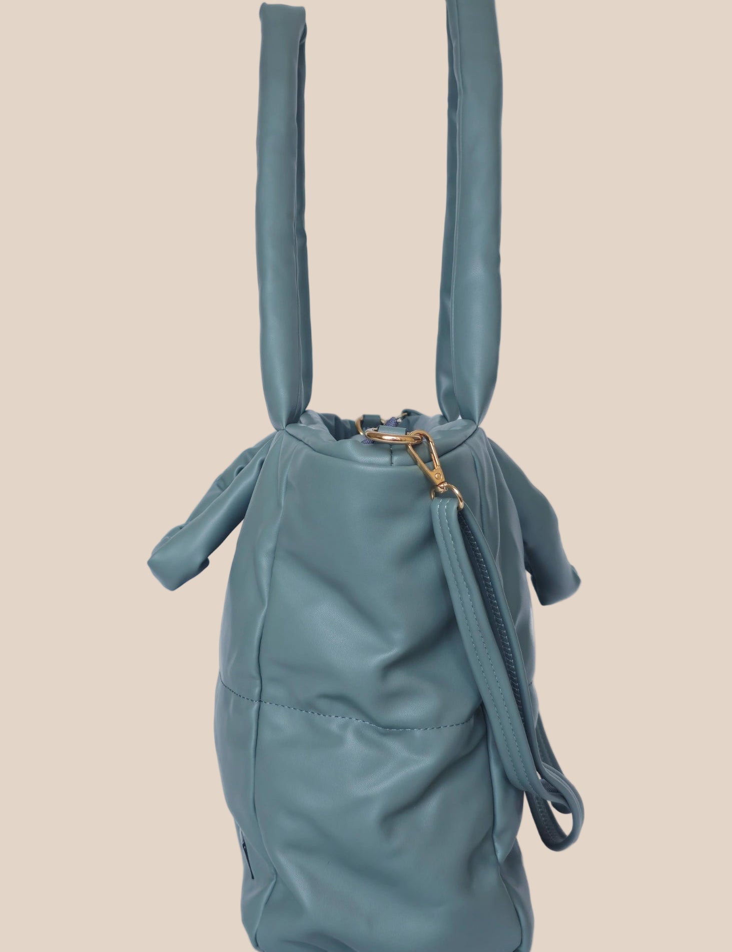 Teal quilted form handbag with a strap and handles side view