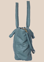 Teal quilted form handbag with a strap and handles side view